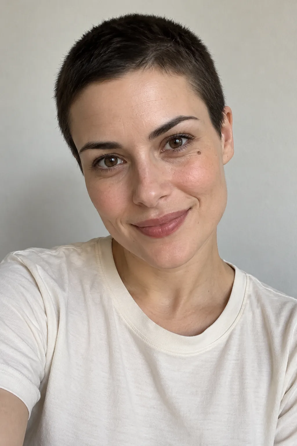 Close-up of an adult with a dark brunette buzz crop and a warm smile.