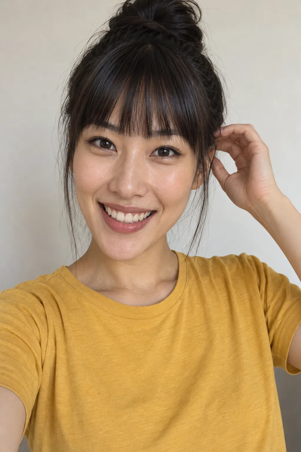 Close-up of an adult with a black top knot and fringe, smiling.
